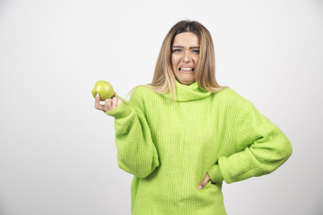 肖像穿着绿色t恤的年轻女子手里拿着一个苹果年轻成人水果