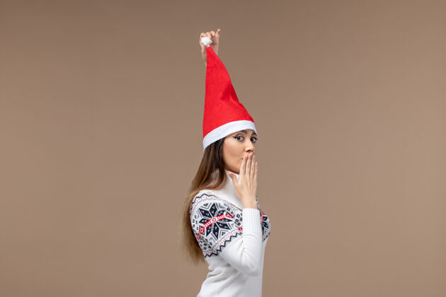 情感正面图棕色背景上戴着圣诞帽的年轻女性圣诞情绪漂亮模特时尚