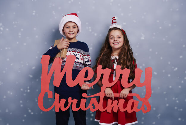 字母带着圣诞装饰品的兄弟姐妹的肖像在降雪中圣诞老人欢乐信息