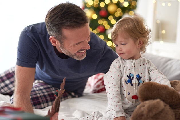 团聚爸爸和他的小女儿一起过圣诞节的早晨圣诞装饰品圣诞树享受