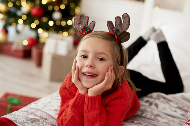 圣诞穿着圣诞服装躺在床上的女孩的画像躺着天真装饰
