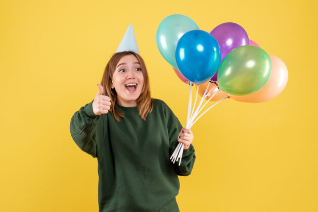 年轻正面图是一位年轻的女士 手里拿着五颜六色的气球快乐年轻的女人吹