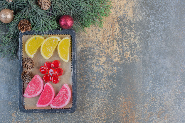 什锦甜甜的果酱和圣诞松果放在深色盘子里高质量的照片果冻糖果糖果
