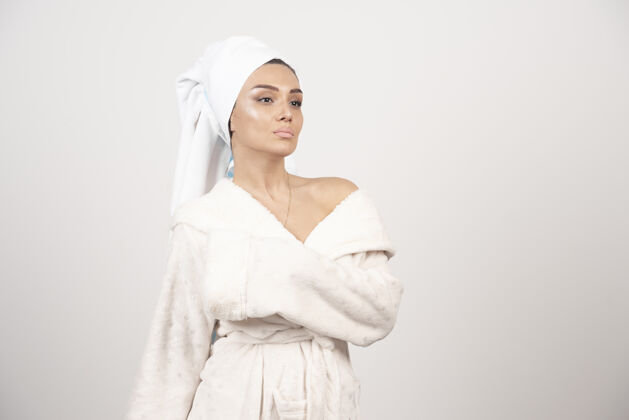 成人穿着白色浴袍的漂亮年轻女子在白墙上摆姿势女性治疗水疗