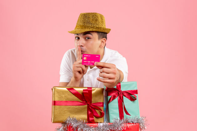 粉红色年轻人在圣诞节前后的正面照片 粉红色的墙上挂着一张银行卡盒子快乐人