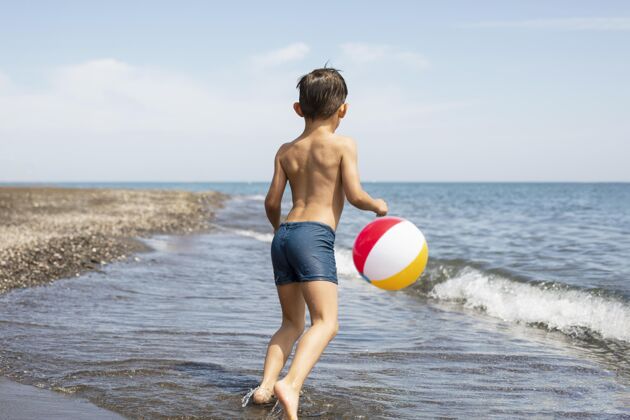 孩子在沙滩上玩球的全垒打小孩生活方式海滩夏天