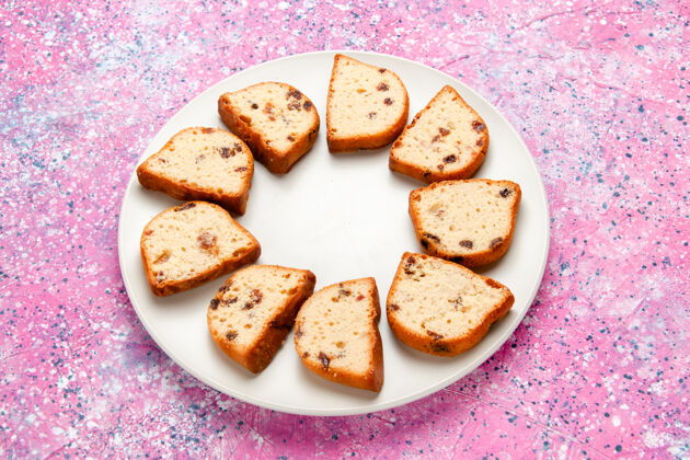 烘焙半俯视图蛋糕片与葡萄干内盘粉红色表面蛋糕烤甜饼干彩色派糖饼干小吃早餐半顶