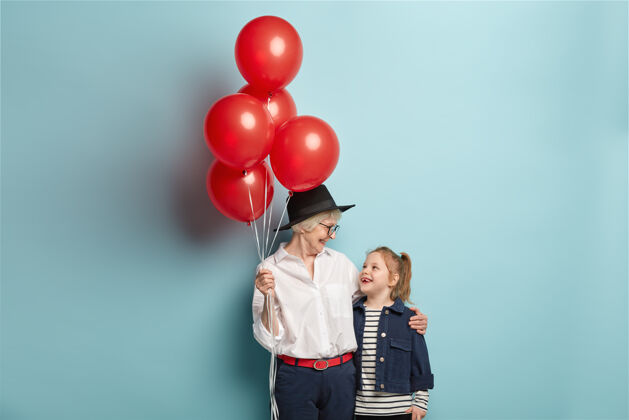 孙女快乐关爱的奶奶手持一束红色气球 祝贺孙女生日成熟深情退休