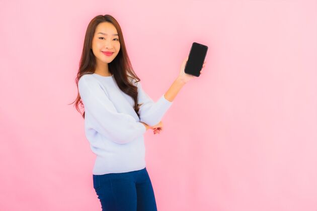 孩子肖像美丽的亚洲年轻女子在粉色隔离墙上使用智能手机电话孩子手机