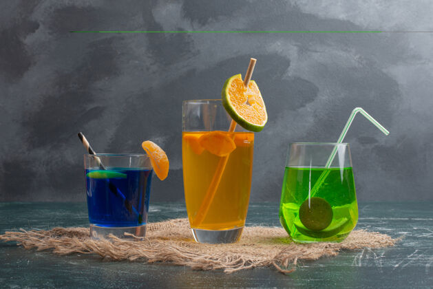 蓝色三杯新鲜饮料放在大理石桌上饮料彩色黄色