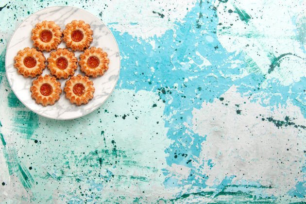 滴俯视美味饼干圆形与果酱形成的浅蓝色背景饼干甜甜饼干面团蛋糕烤浅蓝色饼干视图