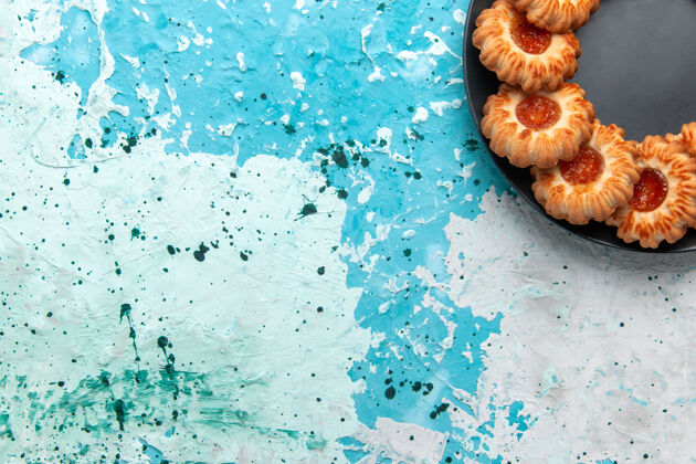 蛋糕俯视美味饼干圆形与果酱形成的浅蓝色背景上黑色盘子饼干糖甜饼干蛋糕背景内部拼图