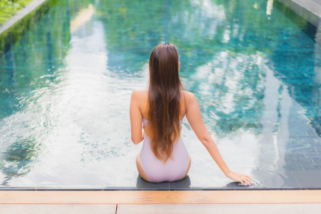 比基尼肖像美丽的亚洲年轻女子放松微笑休闲在酒店度假村的室外游泳池周围游泳池热中国