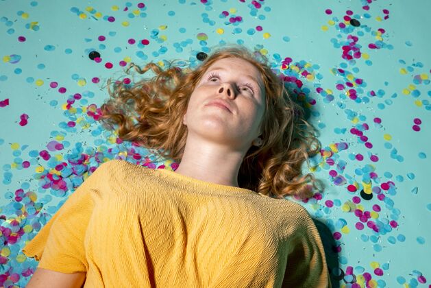 庆祝一个女人躺在地板上 周围有五彩纸屑红发女人五彩纸屑