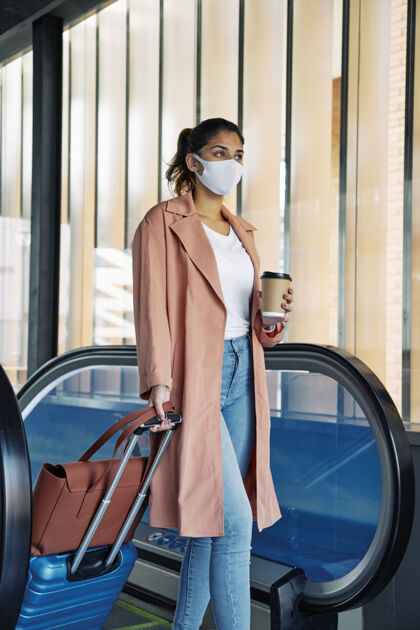 通勤机场大流行期间带着行李和医用面罩的妇女侧视图交通冠状病毒Covid19
