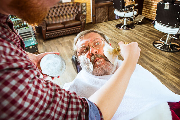理发店这位情绪激动的高级男士正在理发店拜访发型师刷子泡沫奢侈品护理