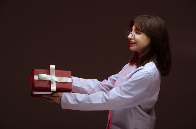 服装年轻的女孩拿着一个红色的礼盒看着盒子青少年模特