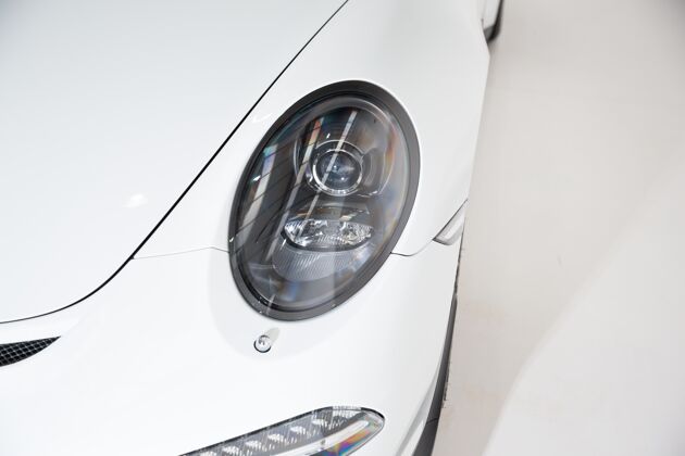 灯一辆白色豪华车的头灯在灰色背景下的特写镜头运输头灯金属