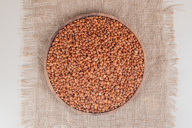 生物把生的棕色豆子放在混凝土上的木盘上板有机成分