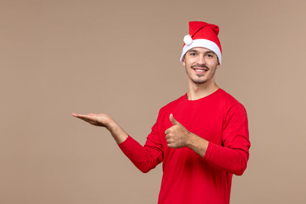 帽子正面图棕色办公桌上微笑的年轻男性情感节日圣诞节制服年轻男性肖像