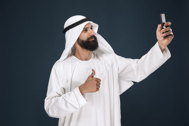 情感深蓝色工作室背景的阿拉伯沙特男人传统茫然衣服