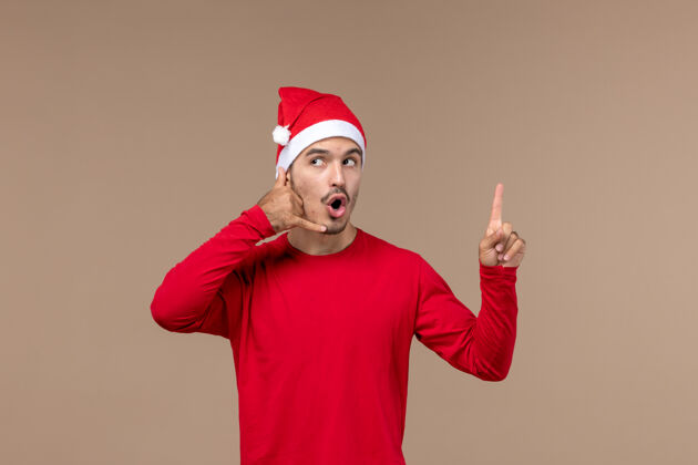 帽子正面图棕色背景上表情好奇的年轻男性圣诞情感节日男性微笑人节日