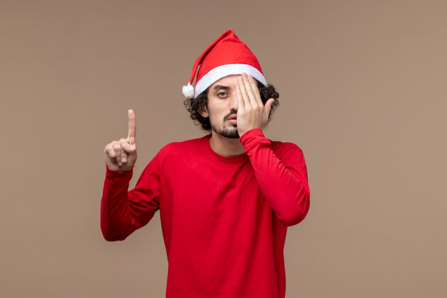 帽子前视图红色的男性覆盖了他的一半脸上的棕色背景圣诞节背景圣诞节成人