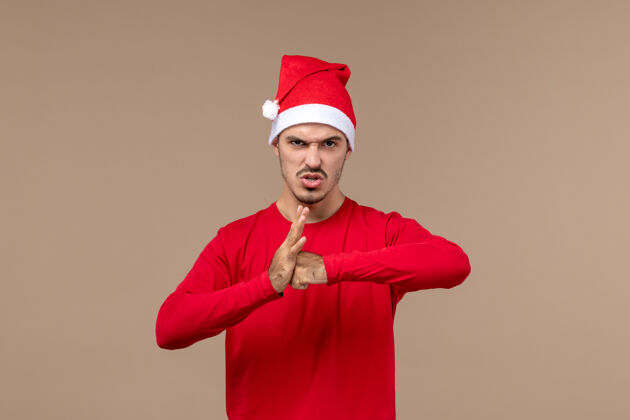 年轻男性正面图棕色背景圣诞情感假期 年轻男性带着愤怒的表情专业服装男人
