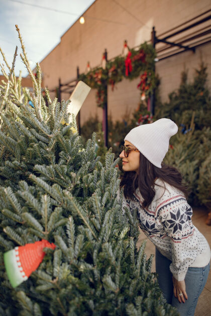 商店优雅的女孩买了一棵圣诞树室内女性毛衣