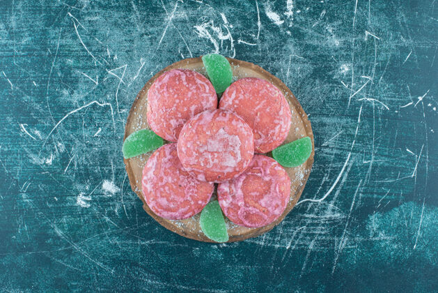 美味在蓝色的木板上涂上粉红色的饼干和marmelades甜点甜点糖