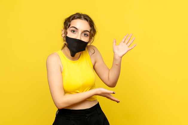 流行病黄墙上戴着黑面具的年轻女子的正视图可爱防护罩人
