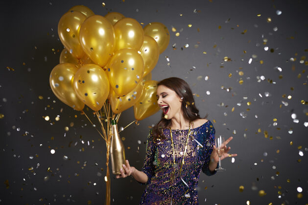 女人在五彩纸屑中放着气球和香槟的女人水平闪光优雅