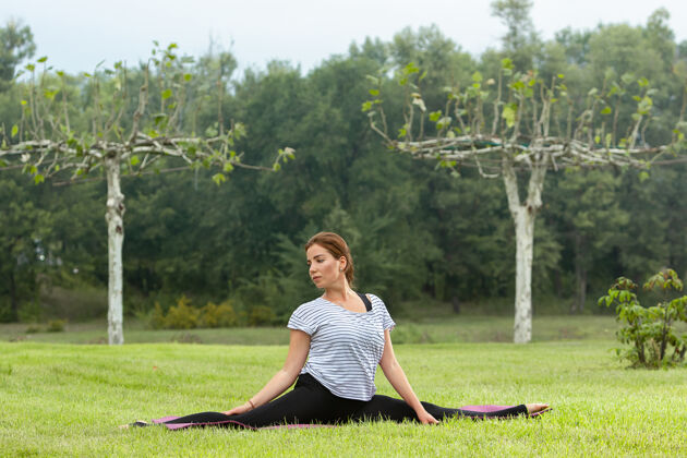 女孩年轻漂亮的女人在绿色公园做瑜伽练习健康的生活方式和健身理念运动健康冥想