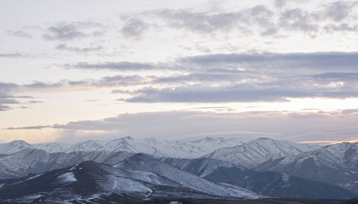 风景远眺白雪皑皑的群山 在多云的天空中欣赏日落的美景俯瞰日落雪