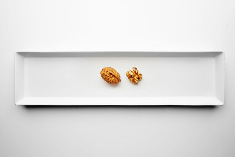 营养胡桃木的封闭和开放隔离在长方形陶瓷板的中间 放在白色的桌子上外壳仁开放