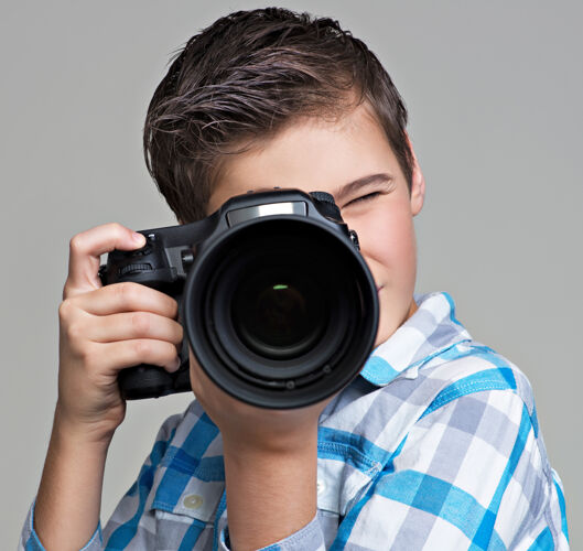 青少年男孩用单反相机拍照十几岁的男孩拿着相机拍照男性专业摄影
