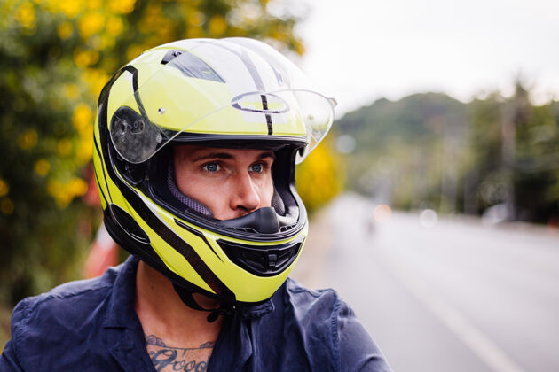 自然在泰国繁忙的公路边骑摩托车的戴着黄色头盔的男摩托车手的画像自行车热带户外