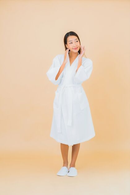女士肖像美丽的亚洲年轻女子穿着米色的微笑浴袍成人头部护理