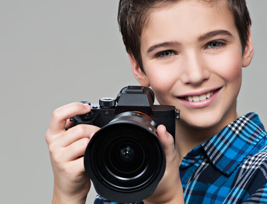 拍摄男孩拿着相机拍照高加索男孩的肖像 手里拿着数码相机摄影灰色外观