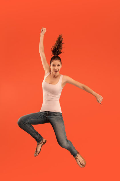 自信在移动中的自由相当快乐的年轻女子跳跃的半空中拍摄充实服装舞蹈