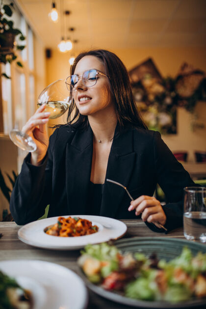 意大利面在咖啡馆吃意大利面的年轻女人餐厅女人快乐叉子
