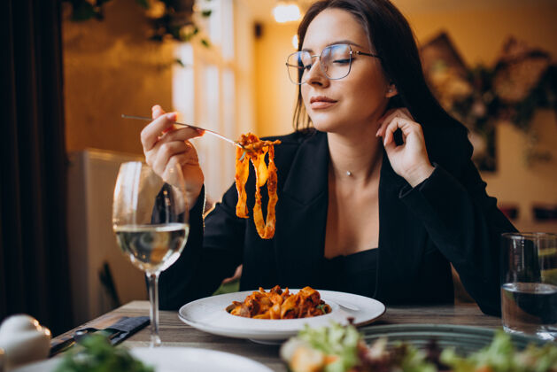 饥饿在咖啡馆吃意大利面的年轻女人美食传统女性