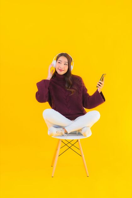 程序员肖像美女亚洲年轻女子用智能手机听音乐兴奋漂亮操作员
