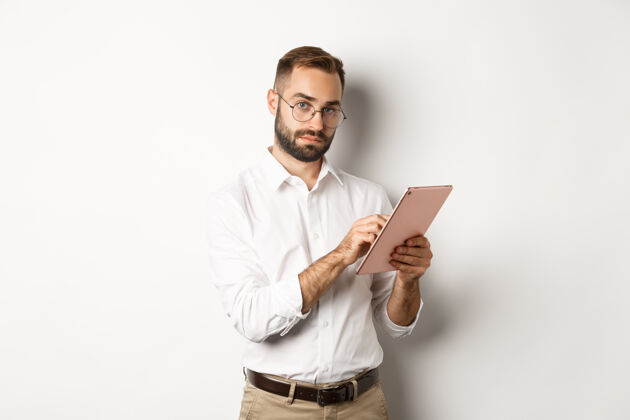 雇主英俊的商人在数字平板电脑上工作 读东西 站着办公室胡子经理