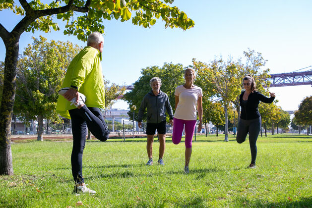 草地一群穿着运动服 在公园草地上晨练的退休积极的成熟人士退休或积极的生活方式的概念公园退休腿部
