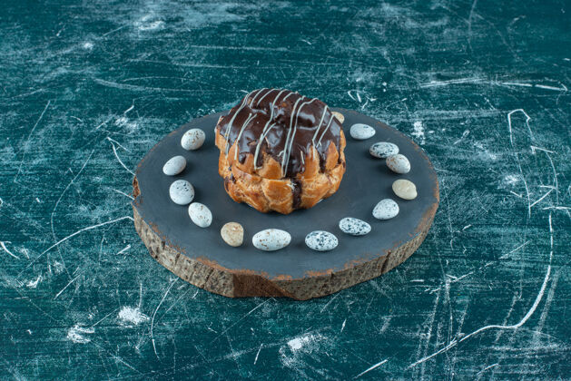 蛋糕巧克力蛋糕和糖果块放在蓝色的木板上配料巧克力甜点