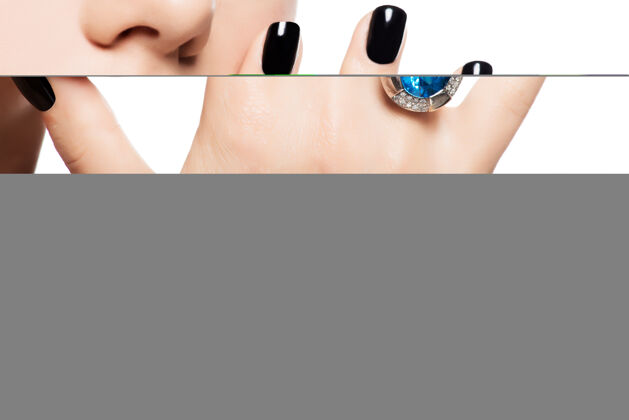 配件一个女人的嘴唇和指甲被涂成亮黑色的宏观照片指甲闪亮戒指