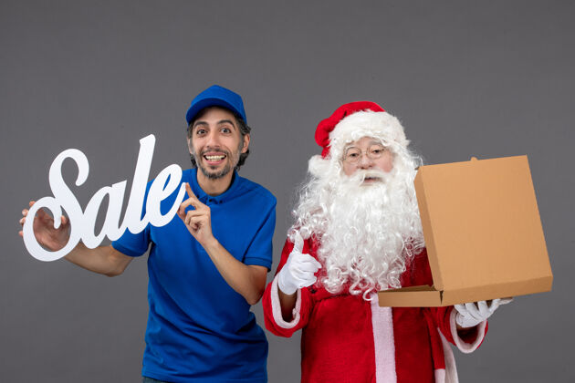圣诞老人圣诞老人的正面图 男信使手持销售横幅 打开灰墙上的食品盒肖像圣诞老人举行