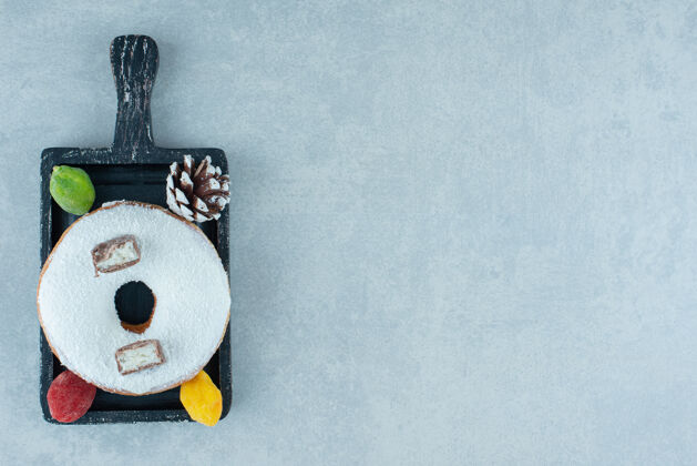 美味松果 marmelades和一个甜甜圈放在大理石上的黑色托盘上顶部视图甜点烘焙