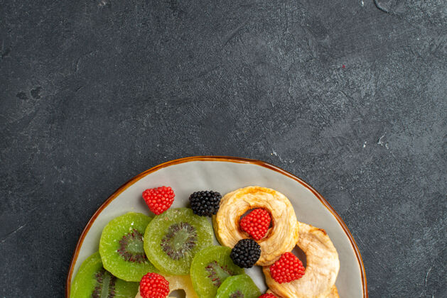 可食用的水果顶部近距离观看菠萝干环 深灰色墙壁上有猕猴桃干和苹果 水果干葡萄干 甜甜的糖果顶部葡萄干菠萝